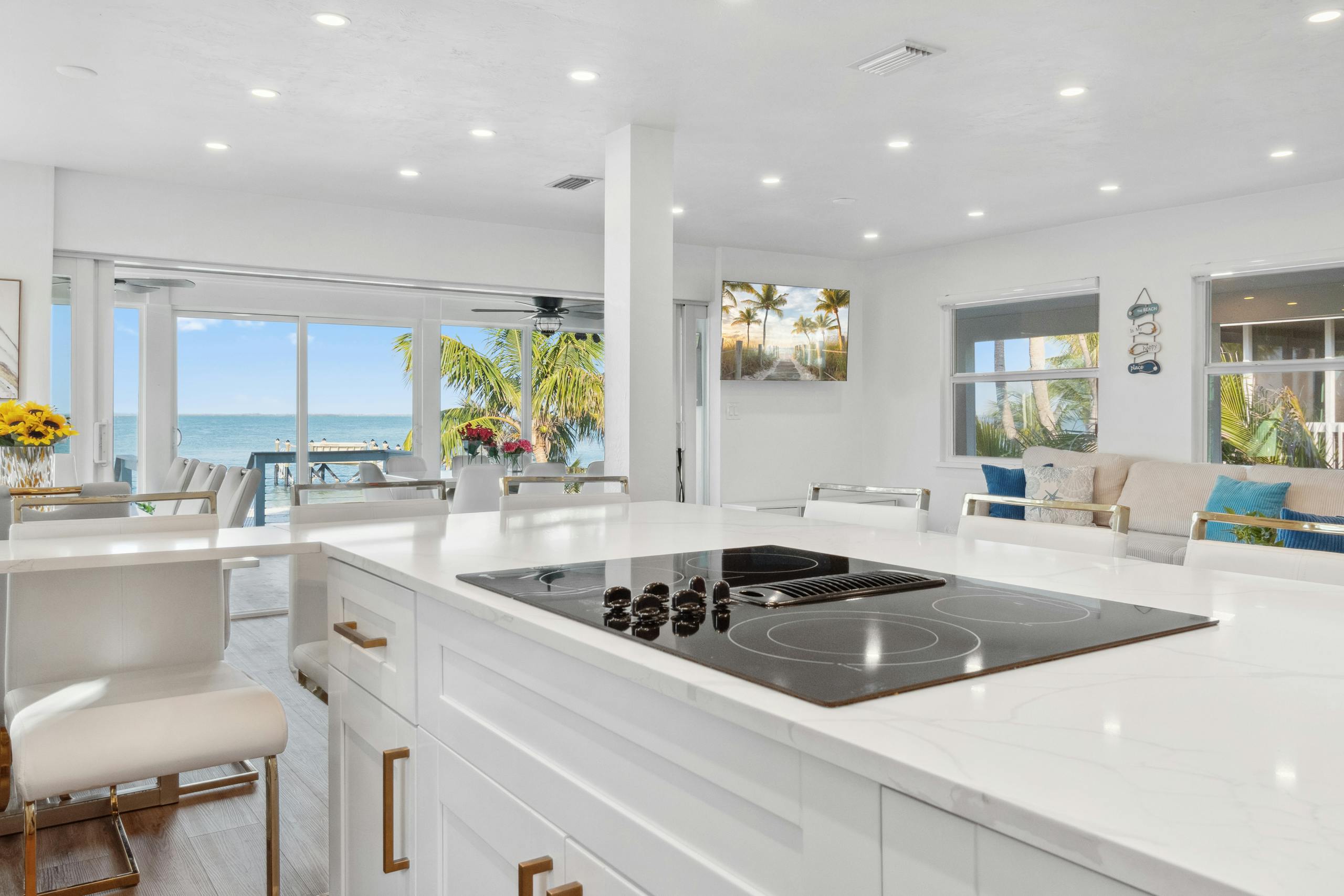Elegant modern kitchen overlooking ocean, featuring sleek appliances and bright decor.